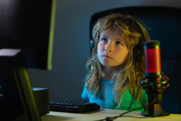 Niño jugando juegos de computadora o estudiando en la computadora de la PC jugador de niños en la iluminación de neón nocturna