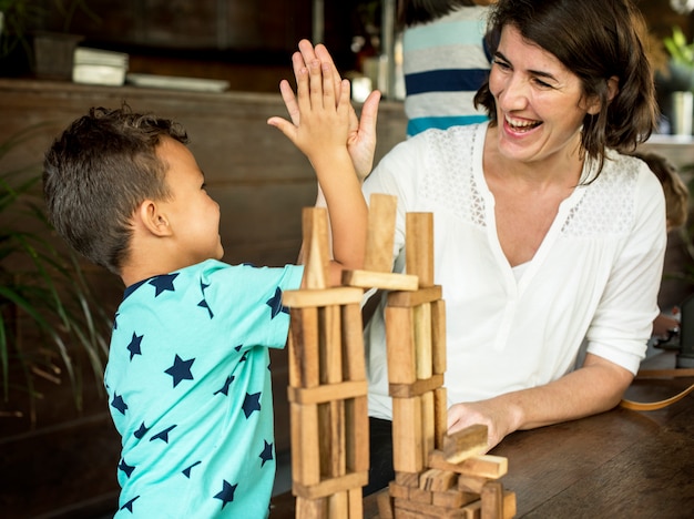 Niño jugando juguete de bloque de madera con profesor