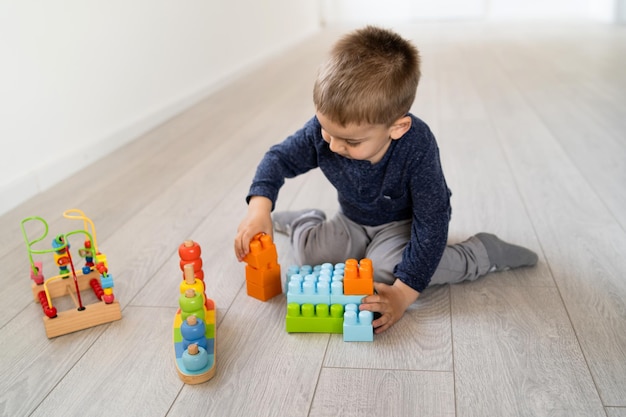 Foto niño jugando con un juguete sentado en el suelo en casa