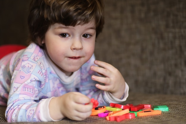 Niño jugando con juguetes pequeños en el sofá de la habitación