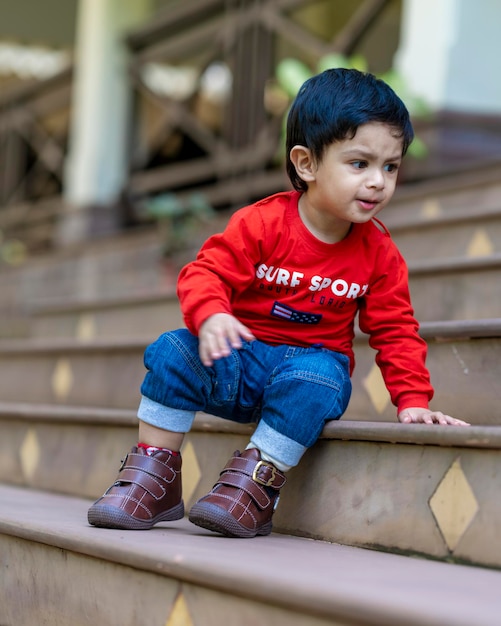 niño jugando con juguetes sentado en las escaleras con camiseta roja y jeans azules