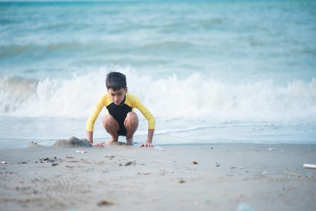 Niño jugando ola y arena en la playa