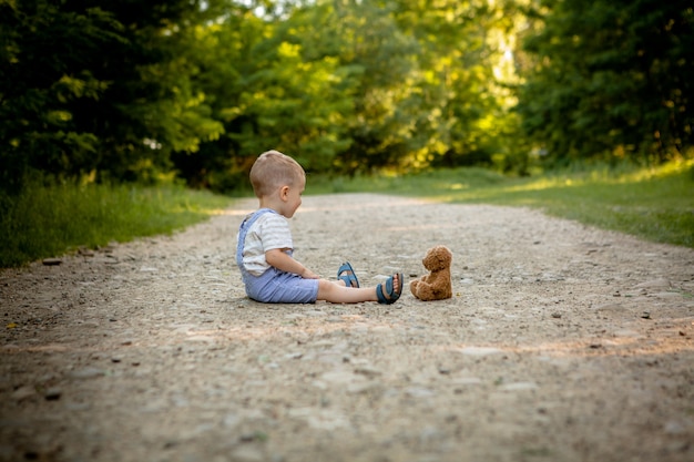 Niño jugando con osito de peluche en la acera.