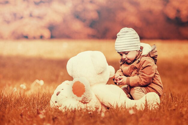 Niño jugando con un oso de peluche en el parque