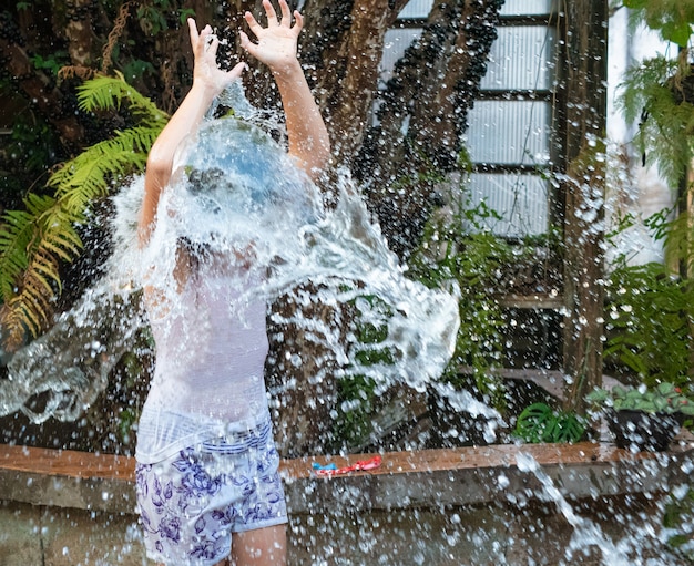 Niño jugando en el patio con agua en el verano brasileño