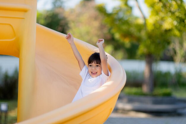 Niño jugando en el patio de recreo al aire libre Los niños juegan en la escuela o en el patio de la guardería Niño activo en un colorido tobogán y columpio Actividad saludable de verano para niños Niñas pequeñas escalando al aire libre