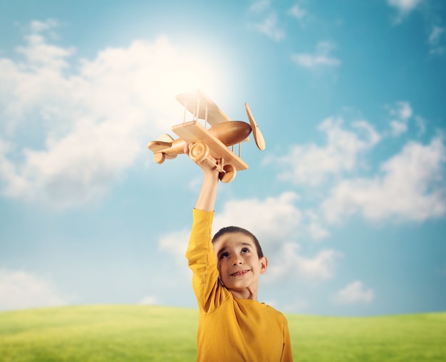 Niño jugando con un pequeño avión de madera vintage