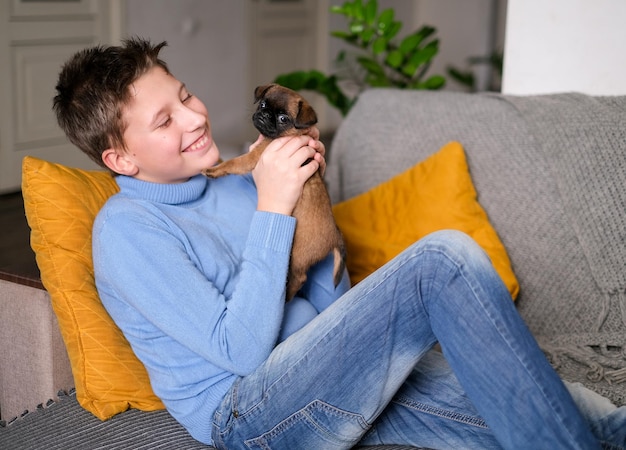 Niño jugando con un perro bebé. Los niños juegan con cachorros en casa. Niño pequeño y leonado o perro brabanson