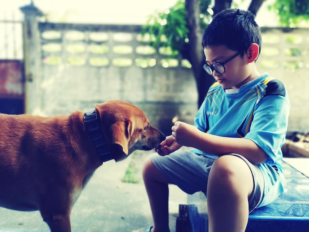 Niño jugando con el perro mientras está sentado en el suelo