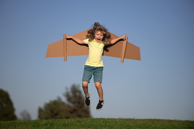 Niño jugando piloto en el fondo azul cielo. Niño soñando. Niño jugando con jetpack de juguete. Piloto de niños divirtiéndose en el parque. Retrato de niño contra el cielo de verano. Concepto de viaje y libertad.