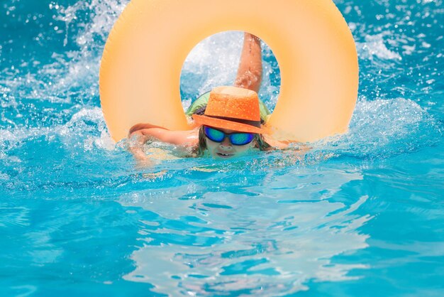 Niño jugando en la piscina Concepto de vacaciones y vacaciones para niños Cóctel de verano para niños Niño feliz con anillo inflable en la piscina
