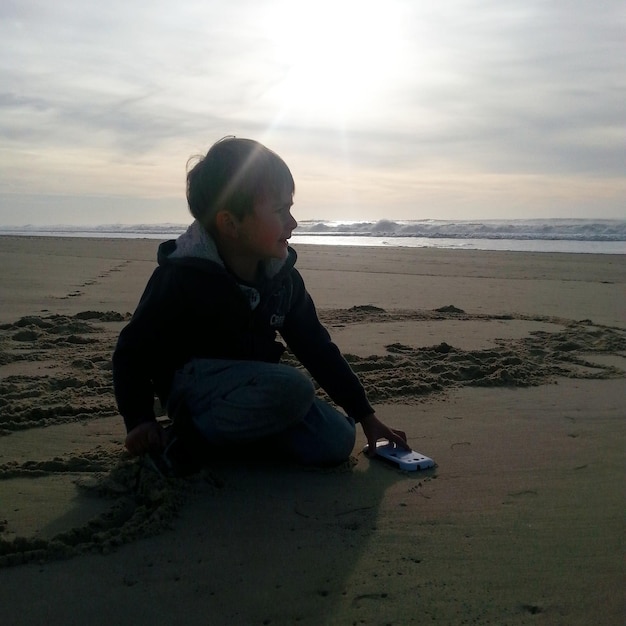 Foto niño jugando en la playa contra el cielo