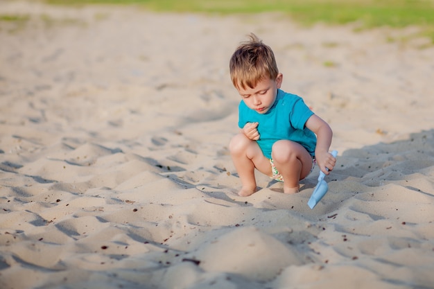 Niño jugando en la playa. Juego de niños en el mar en vacaciones familiares de verano. Juguetes de arena y agua, protección solar para niños pequeños. Niño pequeño cavando arena, construyendo castillos en la orilla del océano.