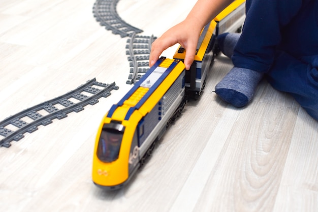 Niño jugando con un tren de juguete en el suelo