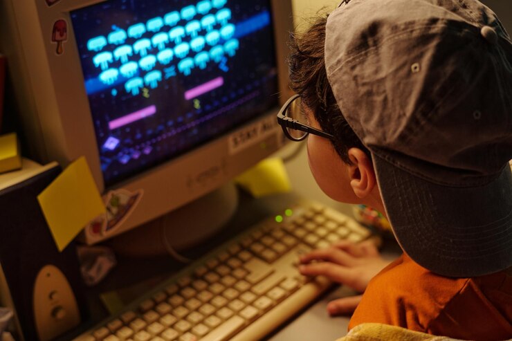 Foto niño jugando a un videojuego retro en una computadora vieja
