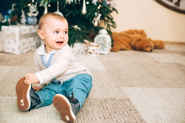 Niño con juguete cerca de decoración navideña y árbol de Navidad