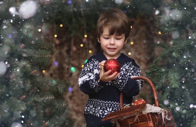 Un niño junto al árbol de Año Nuevo. Los niños decoran el árbol de Navidad.