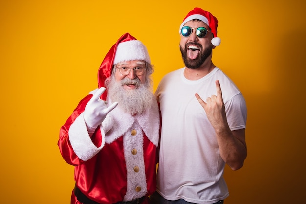 Niño junto a Santa Claus haciendo rock in roll firmar. Santa es un rockero