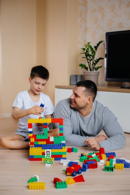 Un niño junto con su padre es interpretado por un constructor y construye una casa. Construcción de una vivienda familiar.