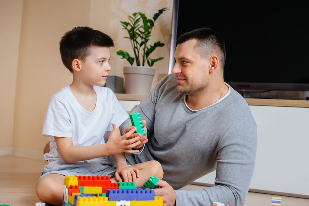 Un niño junto con su padre es interpretado por un constructor y construye una casa. Construcción de una vivienda familiar.