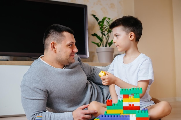 Un niño junto con su padre es interpretado por un constructor y construye una casa. Construcción de una vivienda familiar.