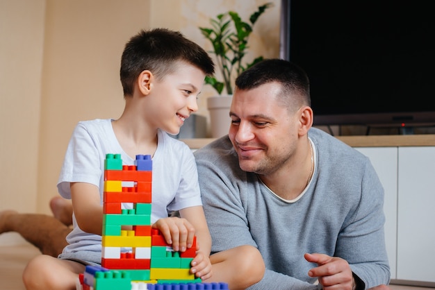 Un niño junto con su padre es interpretado por un constructor y construye una casa. Construcción de una vivienda familiar.