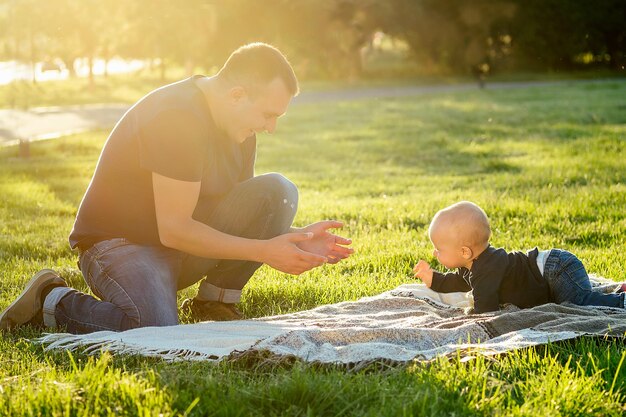 Niño junto con su padre sobre una manta en el parque en verano