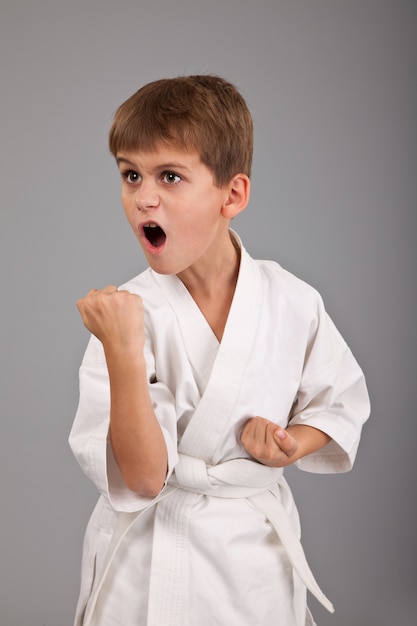 Niño en kimono blanco practicando karate