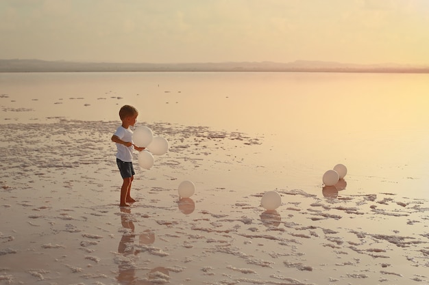 niño en el lago con globos blancos