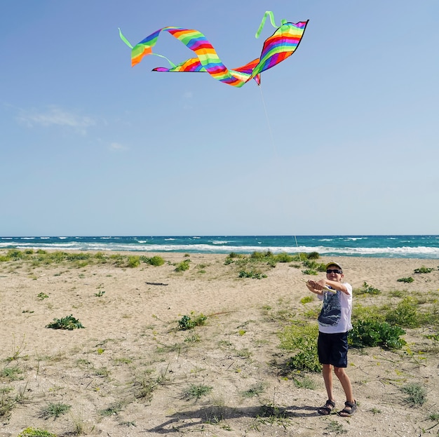 Un niño lanza una cometa en la costa del mar.