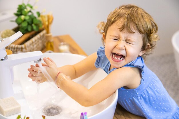 El niño se lava las manos con jabón Enfoque selectivo