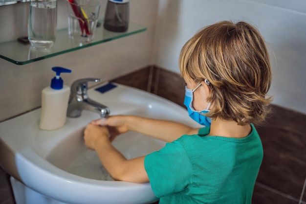 Niño se lava las manos con jabón Niño con una máscara médica debido a la pandemia de coronavirus Quédese en casa Lávese las manos
