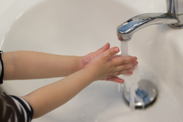 Niño lavándose las manos en el lavabo.