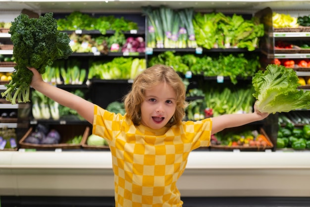 Niño con lechuga, acelgas, verduras, niño de compras en el supermercado, tienda de comestibles, elección de tienda de productos