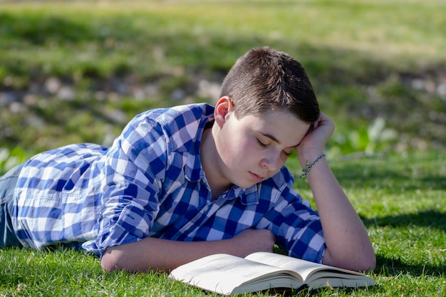 Niño leyendo un libro en el bosque con poca profundidad de campo y espacio para copiar