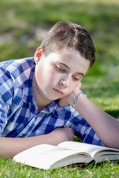 Niño leyendo un libro en el bosque con poca profundidad de campo y espacio para copiar