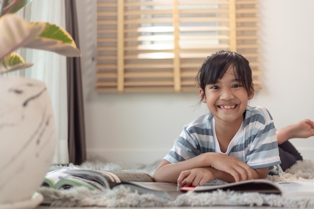 Niño leyendo un libro en casa Niña acostada y leyendo en el interior