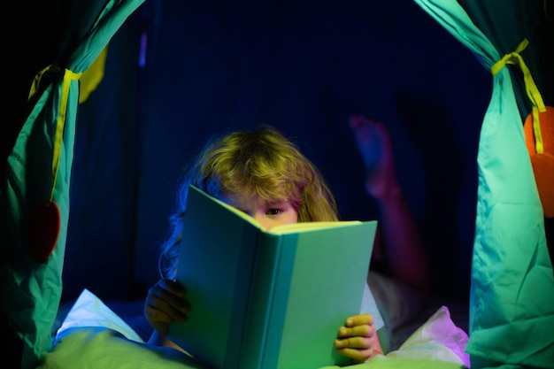 Niño leyendo libros Cara de niños con luz nocturna Concepto de educación y lectura Desarrollo de la imaginación de los niños