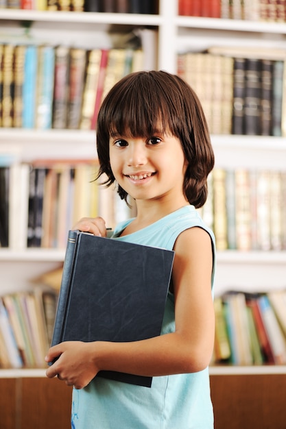 Niño con libro en la biblioteca