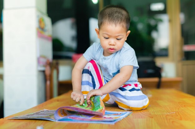 Foto niño con un libro en la mesa en casa