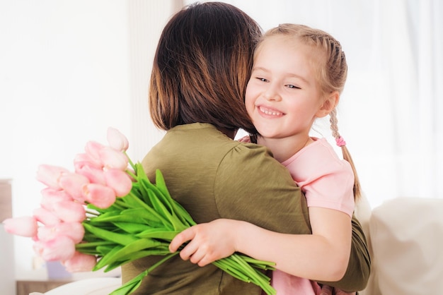 Niño lindo abrazando a la madre con ramo festivo día de la madre