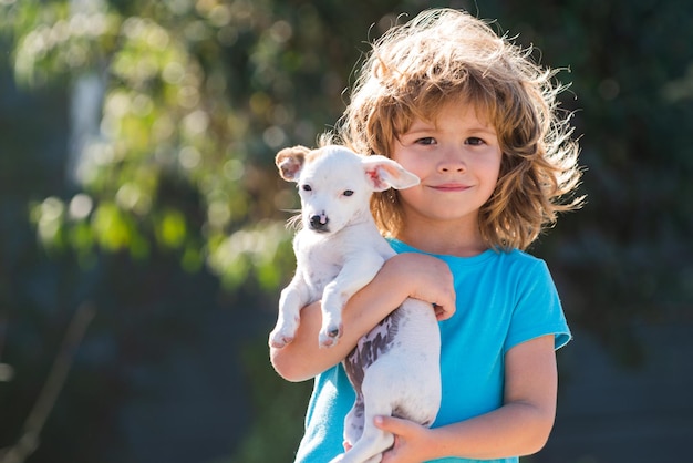 Niño lindo abrazando a un niño y un cachorro de perro jugando afuera