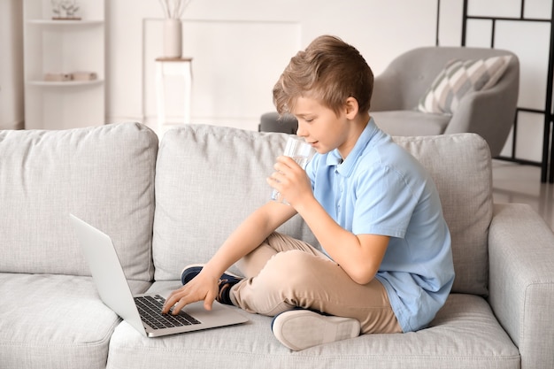 Niño lindo con agua potable portátil en casa