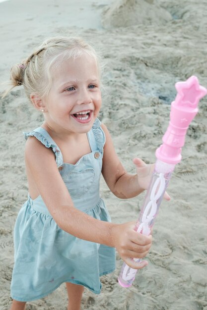 Niño lindo alegre con contenedor de pompas de jabón riendo y disfrutando de las vacaciones en verano