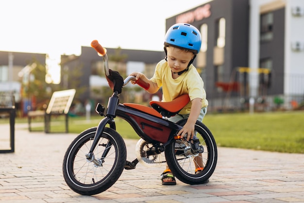 Foto un niño lindo aprendiendo a montar en bicicleta