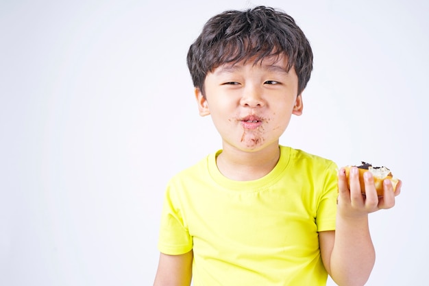 Niño lindo asiático comiendo donut grande aislado en blanco