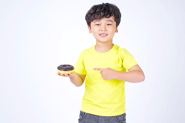 Niño lindo asiático comiendo donut grande