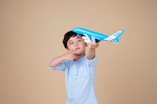 Niño lindo asiático sostiene un juguete de avión