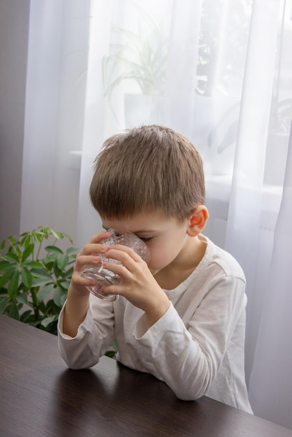 Un niño lindo bebe agua de un vaso