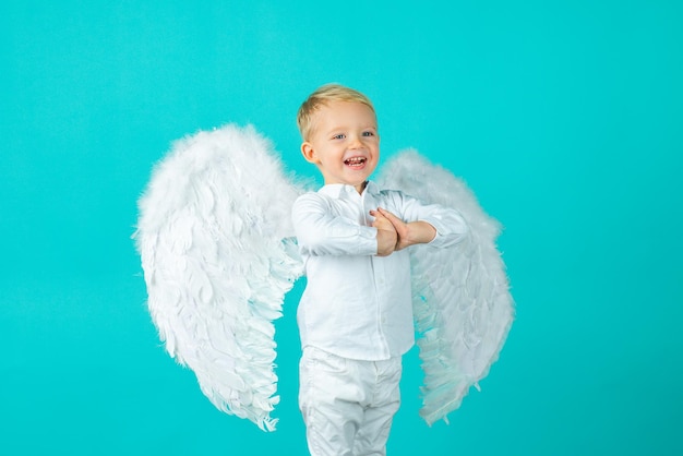 Foto niño lindo bebé con alas de ángel, aislado en azul.